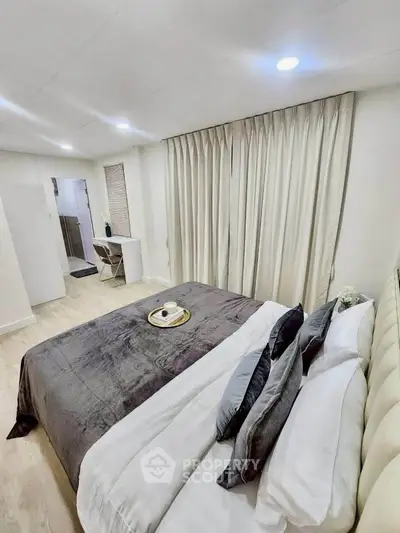 Modern bedroom with elegant decor and cozy ambiance, featuring a plush bed and stylish curtains.