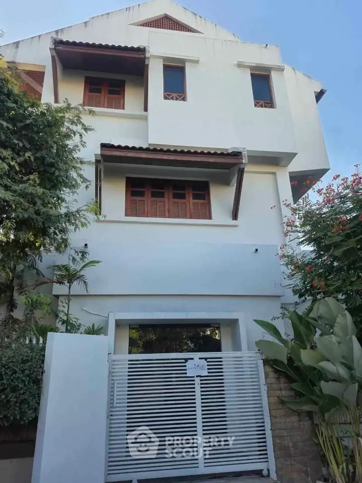 Charming three-story house with modern facade and lush greenery