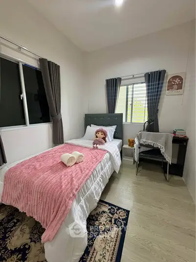 Cozy bedroom with single bed, plush decor, and natural light, perfect for relaxation.