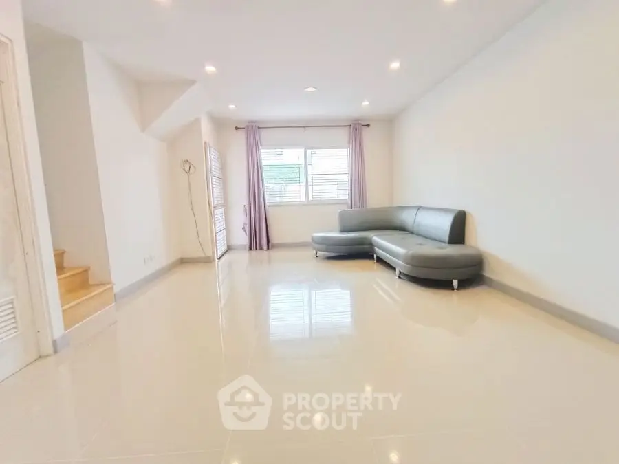 Spacious living room with modern L-shaped sofa and large windows.