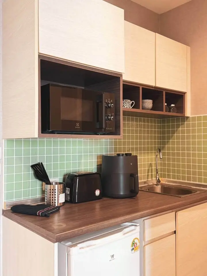 Modern kitchen with microwave, air fryer, and compact fridge in stylish apartment.