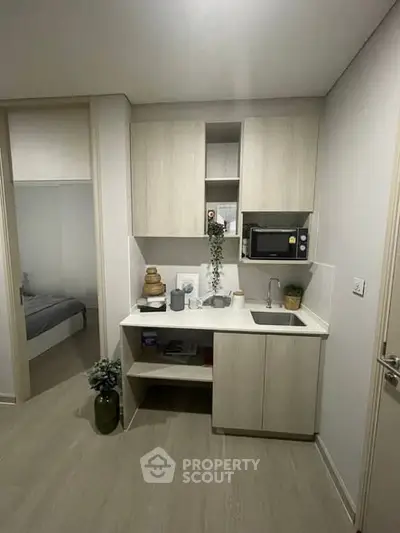 Compact modern kitchen with sleek cabinetry and built-in microwave in cozy apartment.