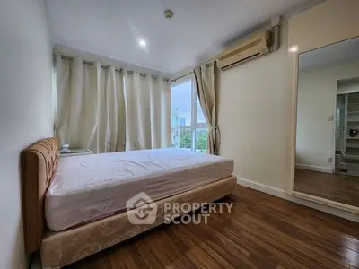 Spacious bedroom with large windows and wooden flooring in modern apartment