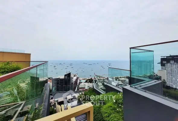 Stunning ocean view from modern high-rise balcony with glass railings.