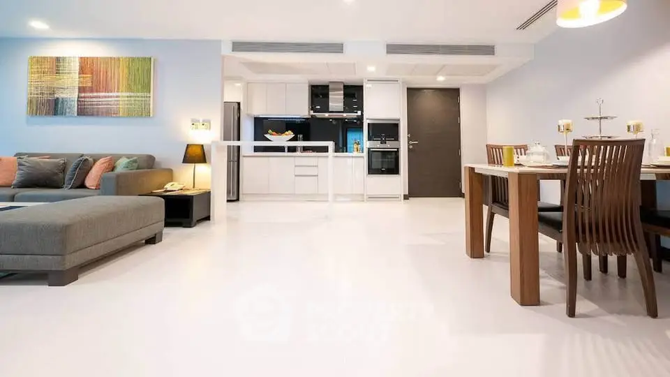 Spacious modern living room with open kitchen and dining area, featuring stylish decor and ample natural light.