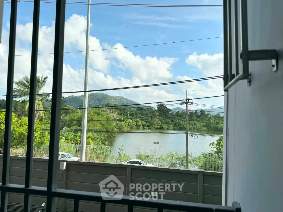 Scenic view from a window overlooking lush greenery and a serene lake, perfect for nature lovers.