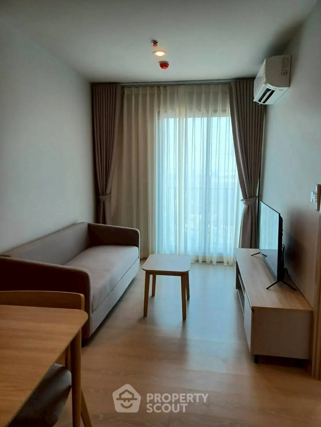 Modern living room with cozy sofa, TV, and large window with curtains.