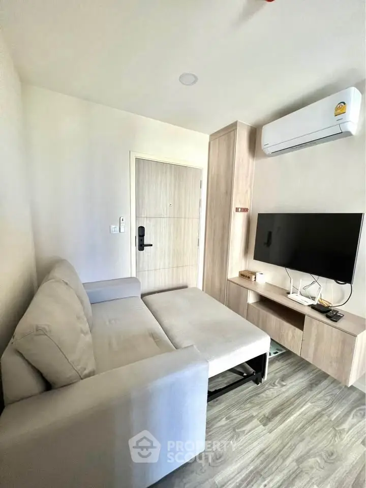 Modern living room with sleek sofa, wall-mounted TV, and air conditioning in a stylish apartment.