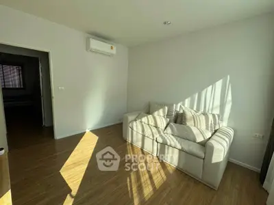 Bright living room with cozy sofa and wooden flooring, perfect for relaxation.