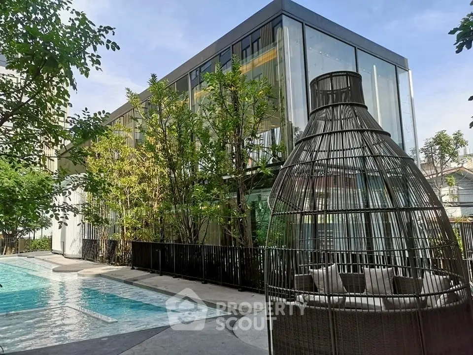 Luxurious modern building with glass facade and inviting poolside seating area.