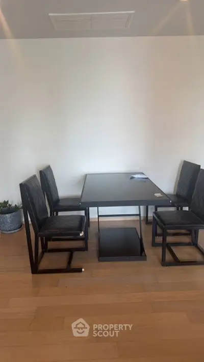 Modern dining area with sleek black table and chairs on wooden flooring.
