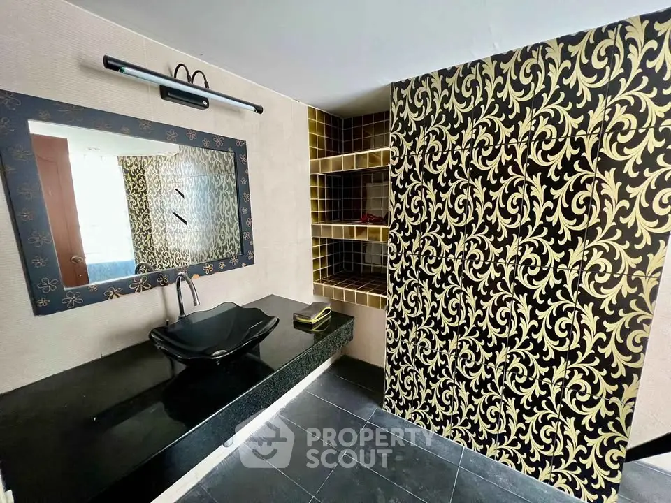 Luxurious bathroom with elegant black and gold decor, featuring a stylish black sink and ornate mirror.