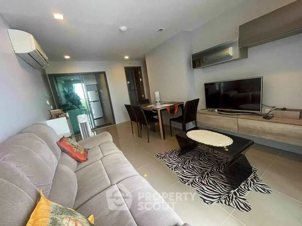 Modern living room with cozy sofa, dining area, and sleek TV setup.