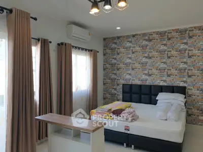 Spacious bedroom with modern decor and natural light, featuring a stylish accent wall and comfortable furnishings.