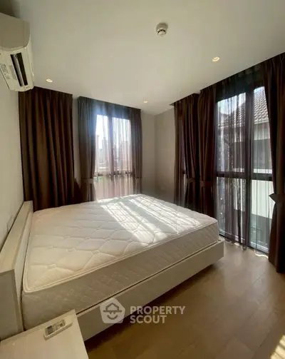 Spacious bedroom with large windows and modern decor in a stylish apartment.