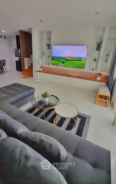 Modern living room with sleek furniture and large TV, perfect for relaxation and entertainment.