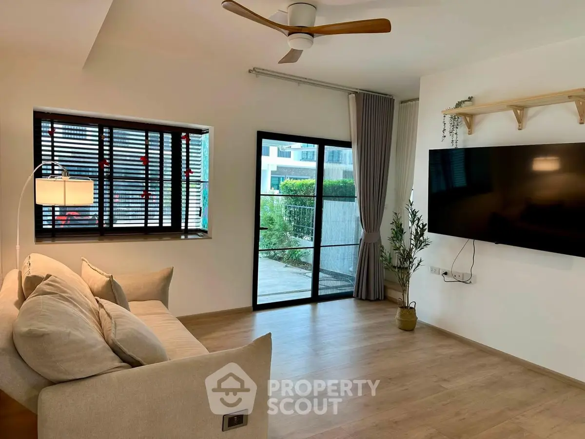 Modern living room with large TV, cozy sofa, and stylish decor in a bright, airy space.