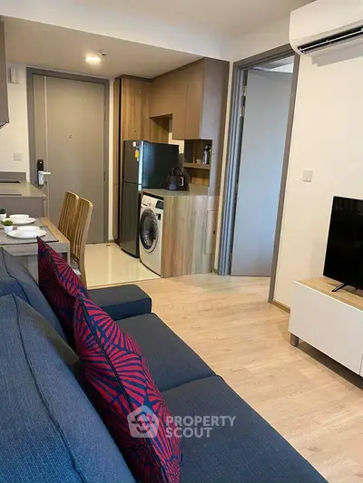 Modern open-plan living room with kitchen, featuring stylish furniture and appliances.
