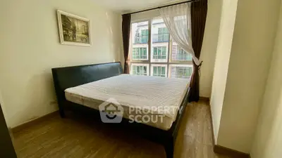 Spacious bedroom with large window and elegant decor in modern apartment.