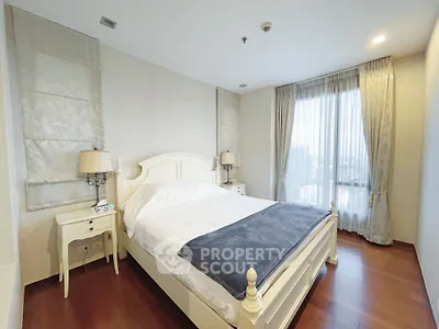 Spacious bedroom with elegant decor and large window offering city views