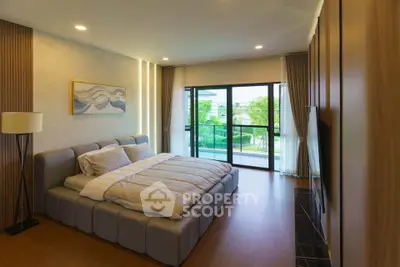 Luxurious bedroom with modern decor and large windows overlooking greenery.