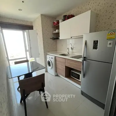Modern kitchen with sleek appliances and dining area in a bright, compact space.