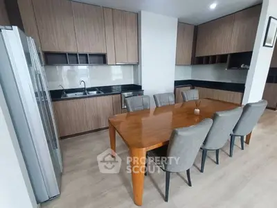 Modern kitchen with wooden cabinets and dining area featuring sleek design and ample seating.