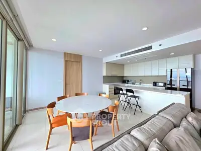 Spacious modern living room with open kitchen and dining area, featuring sleek furniture and ample natural light.