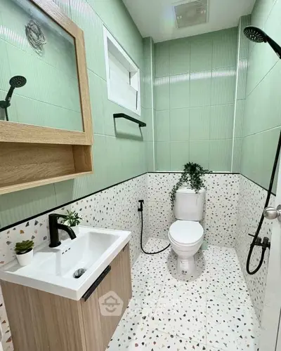 Modern bathroom with green tiles and terrazzo flooring, featuring sleek fixtures and a compact design.