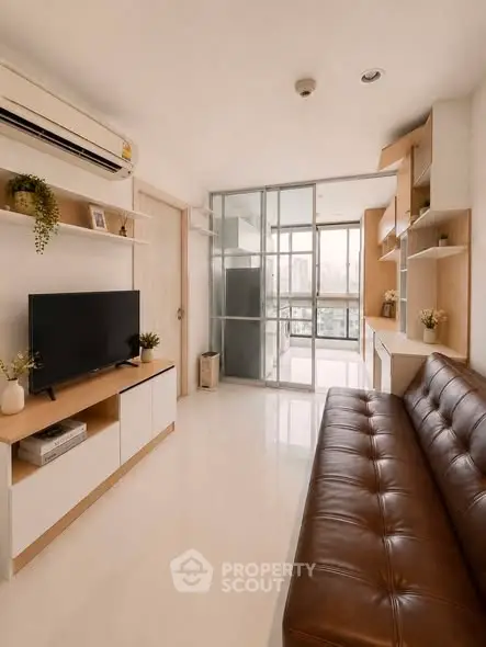 Modern living room with sleek furniture and large windows offering city views.