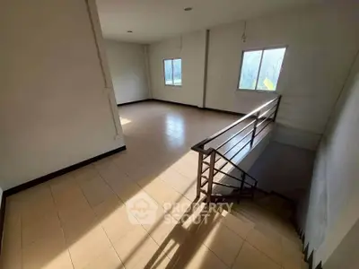 Spacious sunlit room with tiled flooring and staircase, ideal for versatile living space.