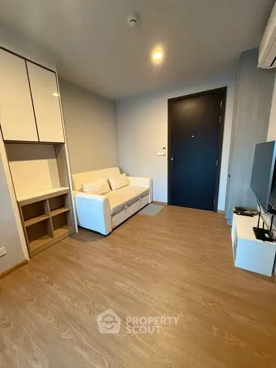 Modern living room with sleek design and wooden flooring, featuring a cozy white sofa and built-in storage.