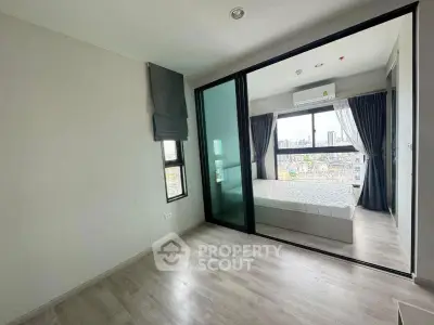 Modern apartment with glass partitioned bedroom and city view, featuring sleek flooring and ample natural light.