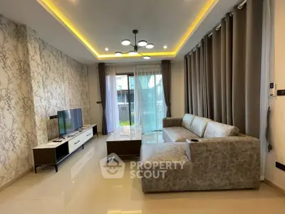 Modern living room with stylish decor and large sofa, featuring elegant lighting and a sleek TV setup.