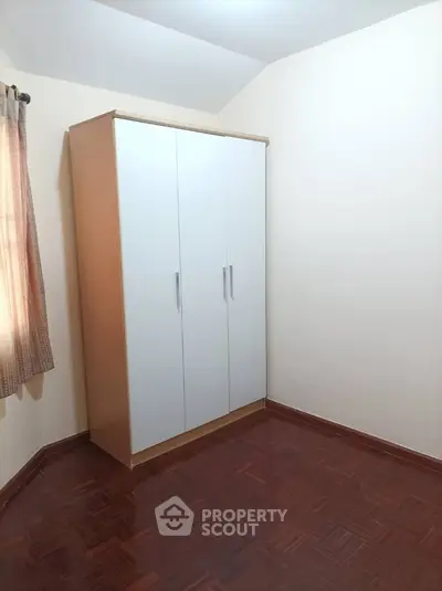 Cozy bedroom space with a large built-in wardrobe and warm parquet flooring, ready for personalization and decor.