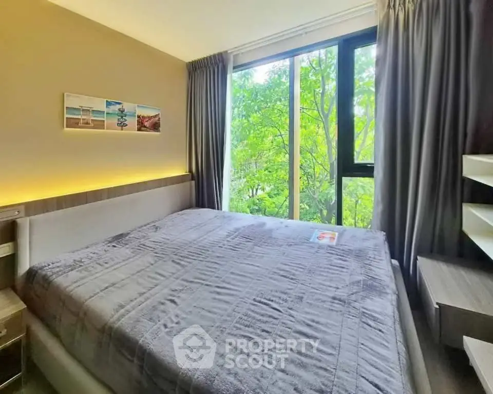 Cozy bedroom with large window and lush green view, perfect for relaxation and tranquility.