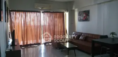 Cozy living room with brown sofa and natural light from large window.