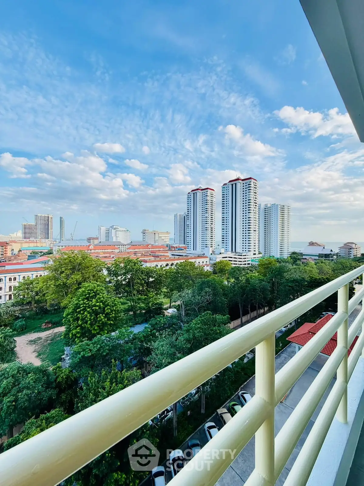 Stunning cityscape view from a high-rise balcony with lush greenery and modern skyscrapers.