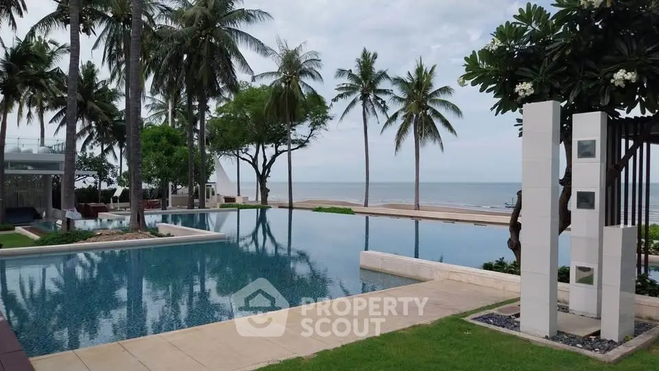 Luxurious beachfront pool with palm trees and ocean view, perfect for relaxation and leisure.