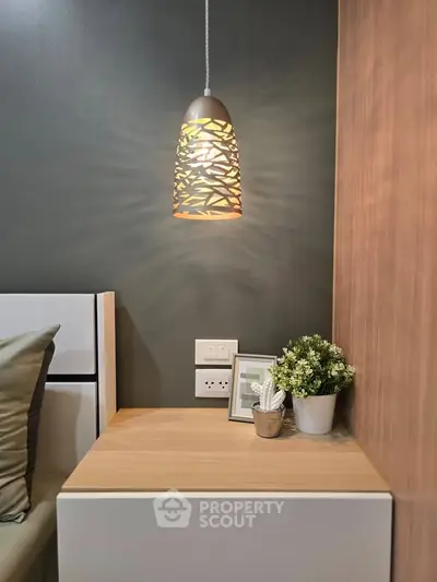 Modern bedroom corner with stylish pendant light and wooden nightstand, perfect for cozy living.