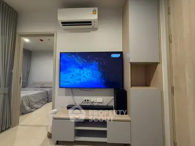 Modern living room with sleek TV setup and air conditioning, showcasing contemporary interior design.