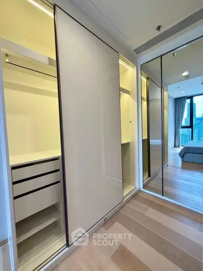 Modern bedroom with walk-in closet and city view, featuring sleek design and ample storage space.