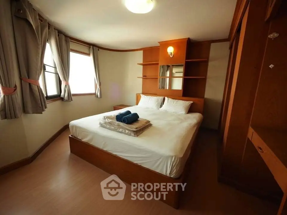 Cozy bedroom with wooden furniture and natural light, perfect for relaxation.