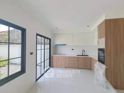 Modern kitchen with sleek cabinetry and large windows offering natural light