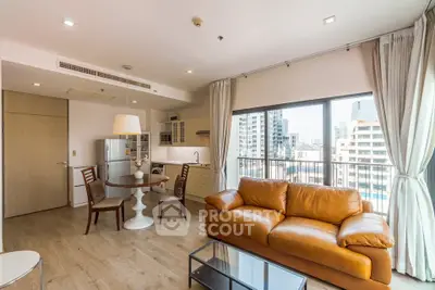 Modern open-plan living room with leather sofa and city view balcony in high-rise apartment.