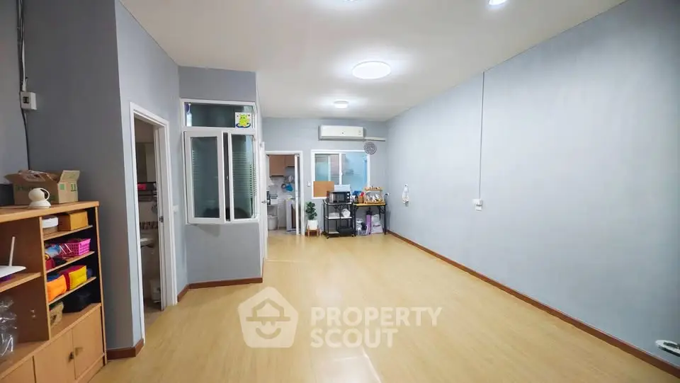 Spacious living room with wooden flooring and modern lighting, ideal for family gatherings.