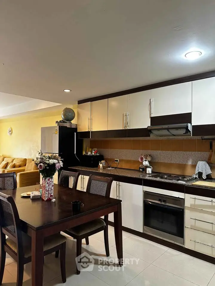 Modern kitchen with dining area featuring sleek cabinets and integrated appliances in a cozy open layout.