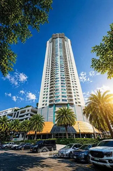 Stunning high-rise building with palm trees and clear blue sky, perfect for luxury urban living.