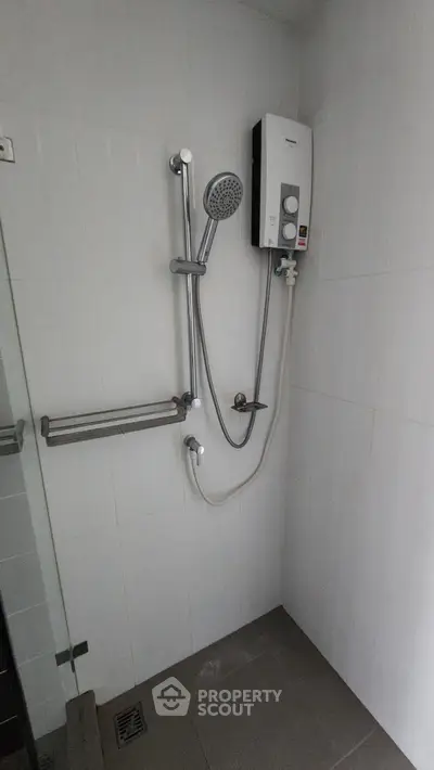 Modern bathroom with shower and water heater in minimalist design.