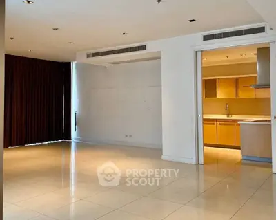 Spacious open-plan living room with adjacent modern kitchen in luxury apartment.